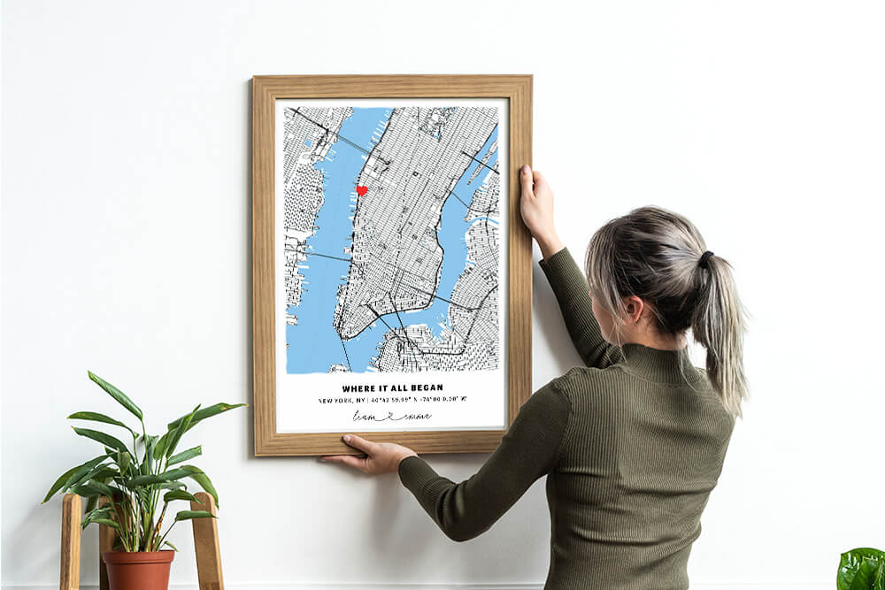 Woman hanging a custom location map frame on the wall